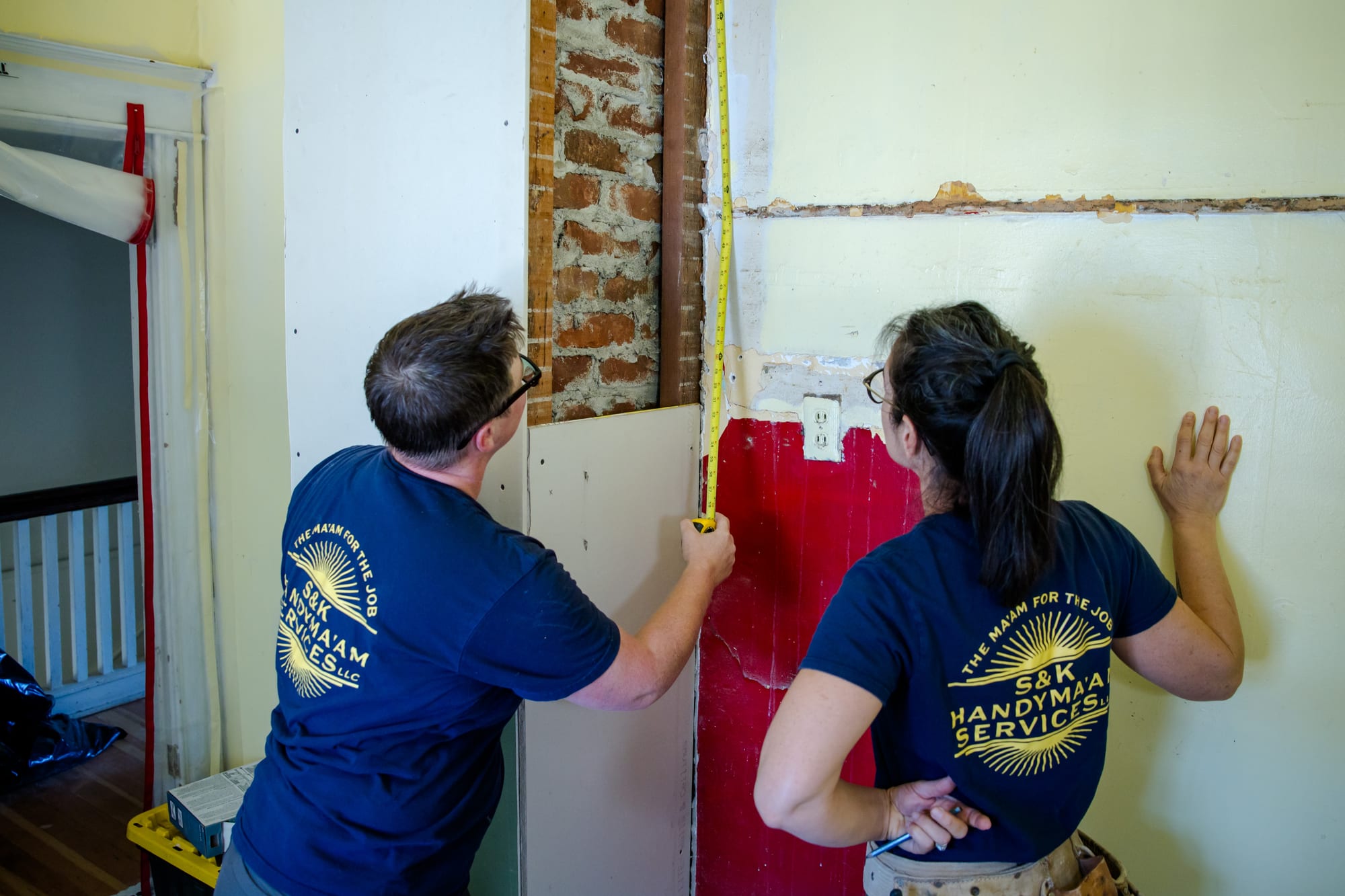 SJ and Lisa measuring and preparing a wall during a home renovation